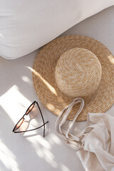 Flatlay of women's fashion accessories. Stylish female sunglasses, straw hat, shopper bag on white...