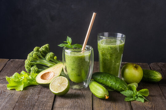 Fresh green smoothie in glass on wooden table, closeup.  Detox diet concept: green vegetables on rustic table. Clean eating, alkaline diet, weight loss food concept.