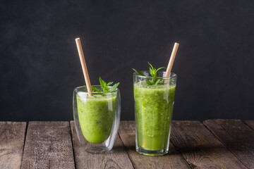 Fresh green smoothie in glass on wooden table, closeup.  Detox diet concept: green vegetables on rustic table. Clean eating, alkaline diet, weight loss food concept.