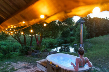 Woman enjoy outside ofuro japanese hot tub in romantic country environment. Idyllic bathtub in the...