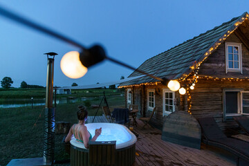 Woman enjoy outside ofuro japanese hot tub in romantic country environment. Idyllic bathtub in the...