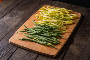 Green and yellow bean pods  on rustic wooden table. Freshly harvested raw beans on wooden desk.