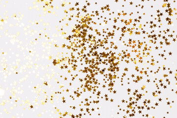 Fototapeta na wymiar Bright gold colored stars confetti scattered on a white background.