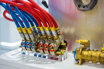 Hydraulic high pressure hoses and valves on mold control system of cooling with red and blue tubes...