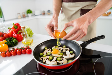 Cropped view portrait of skilled guy cooking healthy lunch dinner cuisine frying bio farm eggs at light white kitchen home indoors
