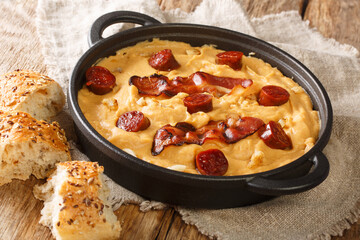 Rustic Gacha Manchega porridge made from pea flour with paprika and garlic, bacon and chorizo close-up in a pan on the table. horizontal