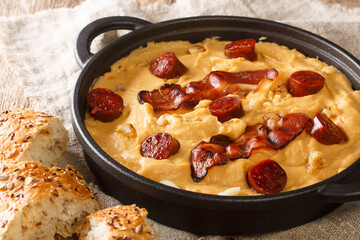 Spanish food Gachas of pea flour with paprika served with bacon and chorizo close-up in a pan on the table. horizontal