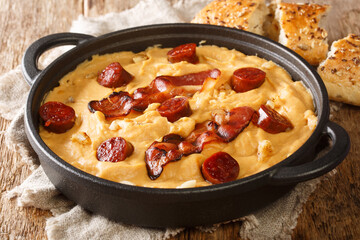 Pea flour gachas manchegas with paprika served with bacon and chorizo close-up in a plate on the table. horizontal
