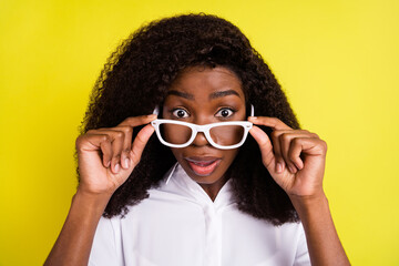 Photo of adorable impressed dark skin woman dressed white outfit eyewear big eyes isolated yellow color background