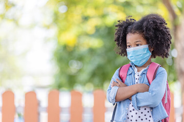 Childhood and back to school - little African American curly hair girl wearing face mask to protect virus and worried look on his face after going back to school again.