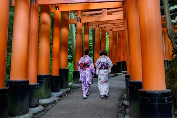 Poster People in traditional Japanese costumes walking on the Torii path of Fushimi Inariaisha temple © Dallas Kwok/Wirestock