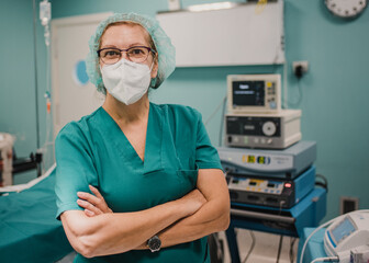 Portrait of female nurse looking at camera inside operating theater at private clinic - Focus on...