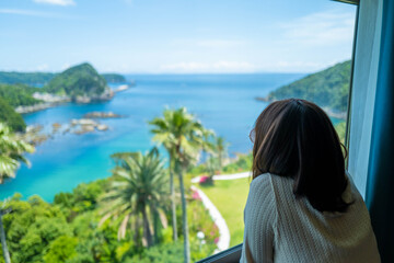 リゾートホテルの窓から絶景を見る女性 A woman looking out the window of a resort...
