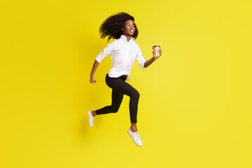Full length body size photo woman jumping high running keeping coffee isolated vivid yellow color background