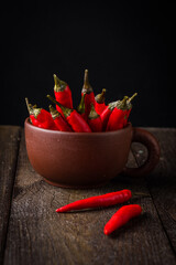 Red chili peppers in a clay chashketna dark background.