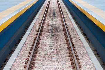 Long and straight line railway train rails in the middle of photo.