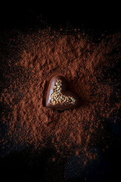 Sweet chocolate candy in shape of heart on dark table