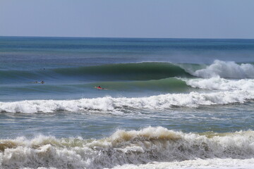 A perfect wave for surfing approaches two surfers