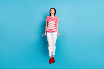 Full length photo of young girl amazed excited shocked surprised jump up isolated over blue color background