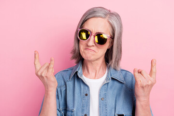 Photo of charming cool mature lady wear denim clothes showing hard rock sign smiling isolated pink color background