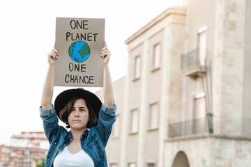 Young demonstrator activist holding banner during climate change protest outdoor in the city -...