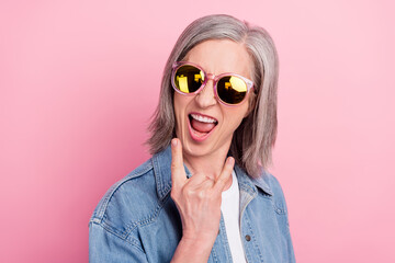 Fototapeta premium Photo of crazy old happy excited old woman make fingers rock sign wear sunglass isolated on pink color background