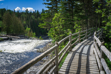 Fototapeta na wymiar Boardwalk leading to the point of view on the Grand Sault waterfall in the Canyon des Portes de l'Enfer nature park in Bas Saint Laurent (Quebec, Canada)