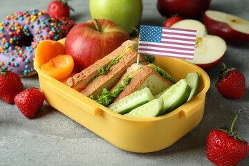 Lunch box with tasty food and american flag on gray textured background