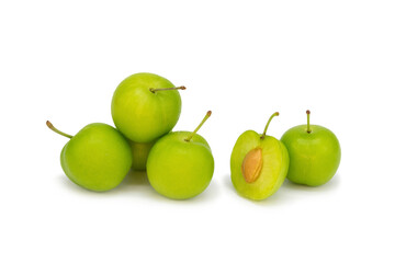 Whole and half green plums on isolated white background