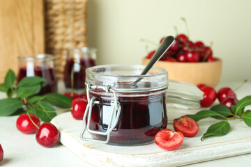 Cherry jam and ingredients on white textured table