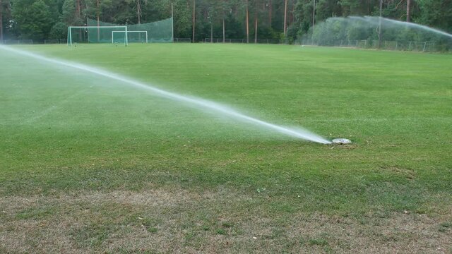 in-ground sprinkler system watering the sports field