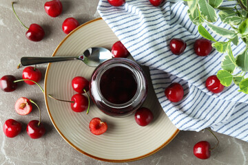 Fototapeta na wymiar Cherry jam and ingredients on gray textured table