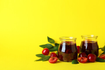 Cherry jam and ingredients on yellow background