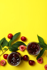 Cherry jam and ingredients on yellow background