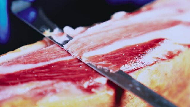 Ham plate. Appetizing traditional Spanish delicious slice Iberian jamón or cured ham leg. Person holding tweezers. Spanish gourmet food. Typical Spanish or Catalan food. Iberian pork. 4k video.