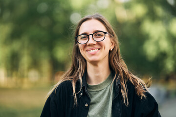 Portrait of a smiling young girl with glasses in the park