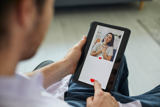 Finding love on modern online dating website or mobile app: Man looking at profile pic of pretty young woman on digital tablet display gives her like and sends her message. Close up, closeup shot