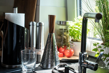 sunny kitchen window with various kitchen utensils and vegetables on the windowsill