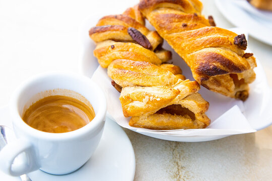 Traditional italian breakfast. Small white cup of hot caffe ristretto and two fresh croissant with apple and nuts. Good morning concept. Daylight. Homemade bakery. Ginseng hot drink and apple pie 