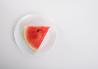 Watermelon on a white plate on a white background, top view