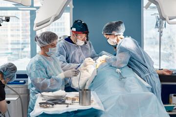 A team of women and men surgeons doing complex heart surgery, cardiovascular surgery, modern...
