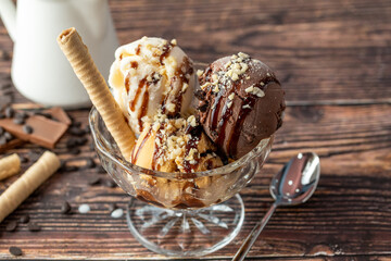 Chocolate, cream and caramel Roma ice cream in a glass bowl with hazelnut and chocolate sauce poured over it.