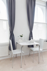 Modern dining area in an urban apartment with plain white walls and bright windows