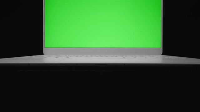 Motorized rising shot of laptop with blank green screen