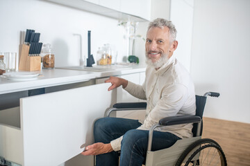 Gray-haired handicapped man in the kitchen smiling nicely - Powered by Adobe