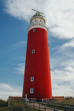 Red lighthouse in the afternoon on texel island close-up against a background of blue sky and white clouds, vertical photo
