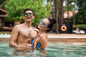 Smiling woman holding hand of boyfriend in swimming pool