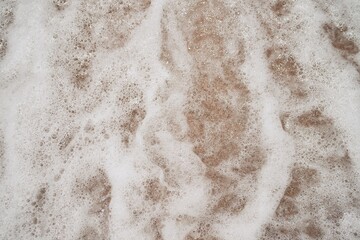 Ocean foamy wave on the sandy beach background    