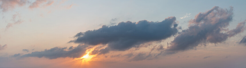 Cloudy evening sky. Sunset. Sun low over the horizon.