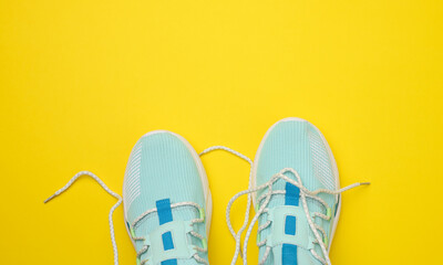 pair of blue textile sneakers on yellow background